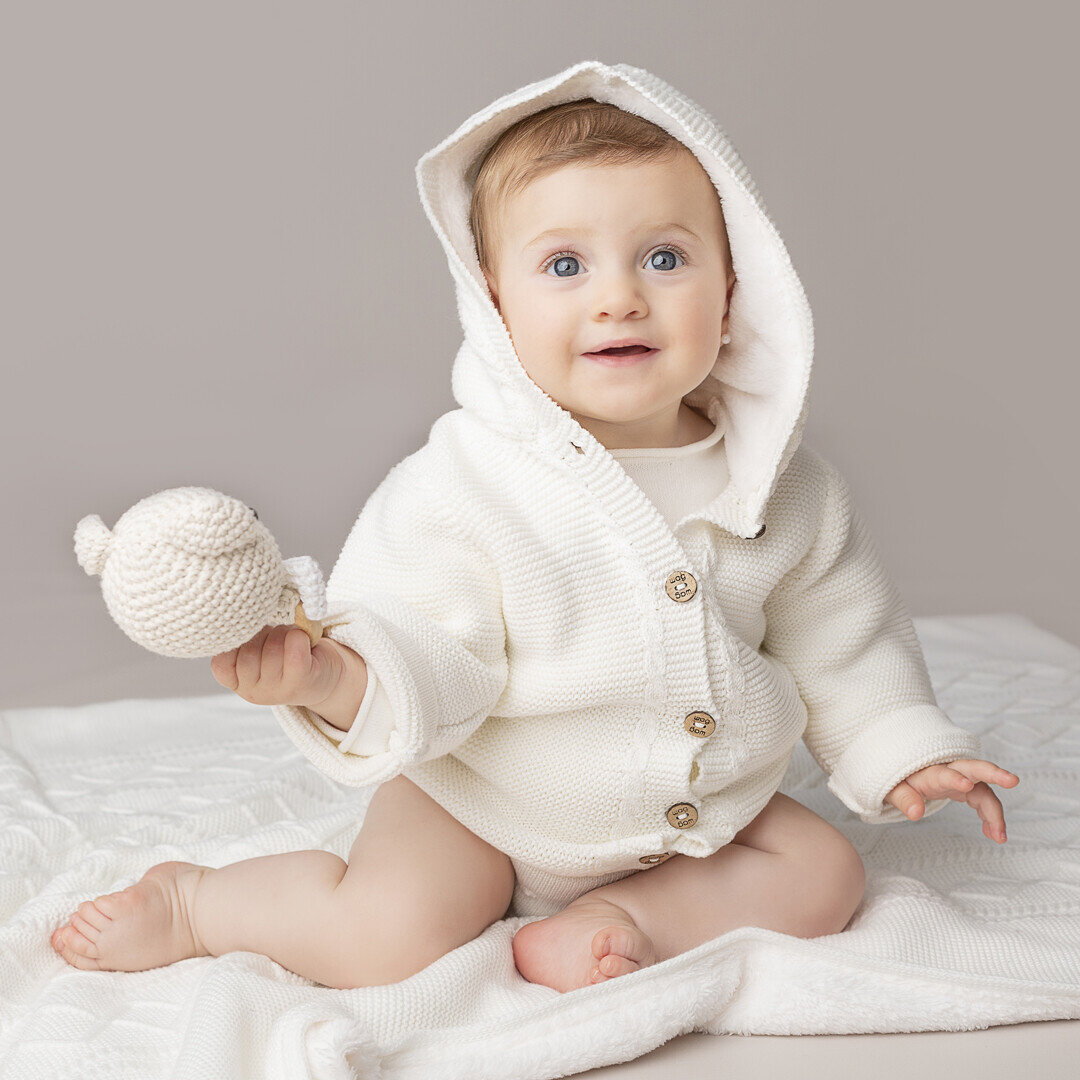 Bebé con abrigo tejido blanco con capucha de WAG
